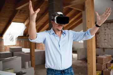 Fototapeta premium good looking male architect with virtual reality goggles and blue shirt on construction site in loft, attic