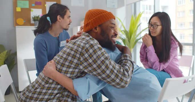 Diverse smiling people hugging in support group meeting