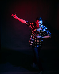 A young man in a studio on a dark background with a multicolored light