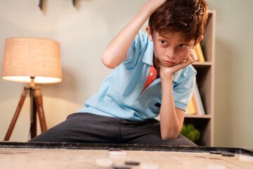 Overthinking Confused Caucasian kid scratching head to decide which coin to hit while playing carrom board - concept of mental illness and development - obrazy, fototapety, plakaty