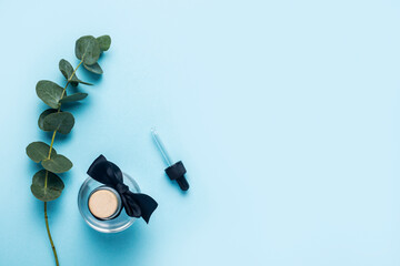 bottle of eucalyptus essential oil, green eucalyptus branch against blue background. Top view, flat lay