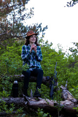 Young girl hunter in a hat drinks tea from a thermos at a halt, soft focus, small creative noise