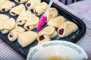 a woman greases the pies prepared for baking with egg yolk for shine
