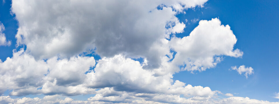 Wide panoramic picture of Cumulus clouds on blue summer sky