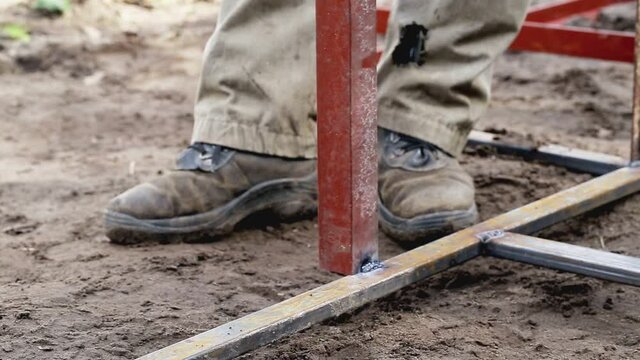 A worker welder using a welding machine welds a metal structure during construction, industry
