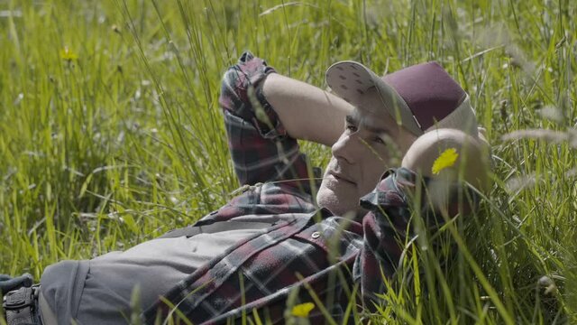 50-year-old man with cap laying in field, enjoying sunny day