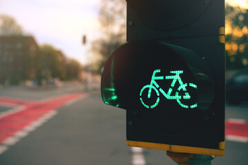 bicycle traffic light in yellow housing showing green light at an urban intersection in colorful sunny bright light at sunset - selective focus with excessive blur