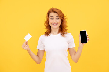 Naklejka premium excited young lady isolated overyellow background using mobile phone holding credit card.