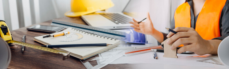 engineer working at a drawings of house in office for discussing. Engineering tools and construction concept.