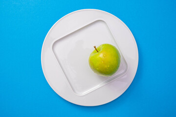 a white plate with a green apple stands in the center