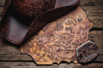 A pirate tricorn hat and treasure map on the old wooden table background.