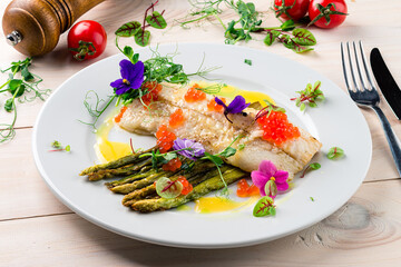 Fish fillets with asparagus and slice of lemon on a plate