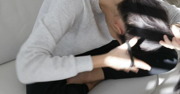girl making her ponytail with her hands on her couch