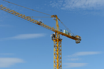 Construction tower crane with cab on blue sky background