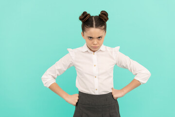 Disobedient girl child back to school standing with arms akimbo blue background, disobedience