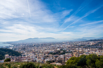 European city landscape next to the coast and mountains with a blue sky. Malaga city next to the Mediterranean Sea.