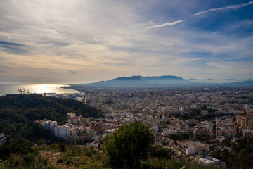 Beautiful landscape of European city next to the port and the mountain at sunset. Malaga city next to the Mediterranean Sea.