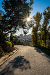 Road through the mountain with the city in the background. Empty path on a sunny day.
