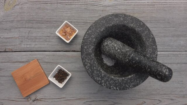 Top view of male hand putting peppercorns, sea salt and sugar into the mortar