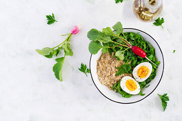 Breakfast oatmeal porridge with boiled eggs, radish and green herbs. Healthy balanced food. Top view, above