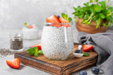 Chia pudding with fresh strawberry and blueberry on top in a glass jar. Healthy breakfast. Copy space.