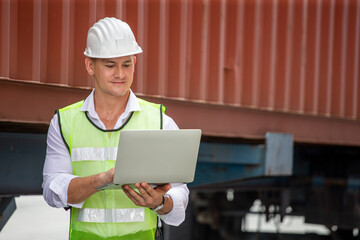 Foreman using laptop computer checking inventory control loading Containers at warehouse logistic in Cargo freight ship for import export. engineer and Communication of transportation