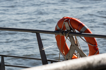 an orange life ring hangs on a metal railing in the harbor of hamburg in the sunshine