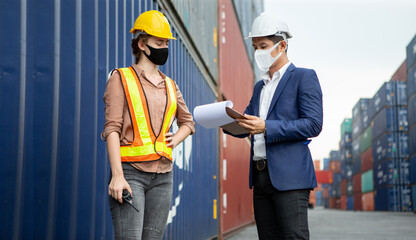 asian businessman using clipboard and harbor worker woman  wareing face mask checking list inventory loading Containers box at warehouse logistic in Cargo during coronavirus, covid 19 pandemic