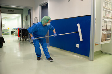 Woman from the cleaning service of a hospital cleaning the walls of the pre-operating room with a...