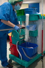 Woman in the cleaning service of a hospital wringing a special brush in her cleaning tower before...
