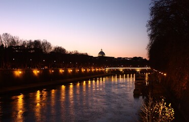 Naklejka premium view of a cathedral at sunset over a river in rome