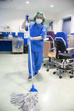 Woman From The Cleaning Service Of A Hospital Cleaning The Floor Of The Operating Room With A Mop. Sanitary Concept