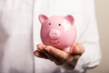 Piggy bank in hand on light background, space for text. Finance, saving money. Business to success and saving for retirement concept