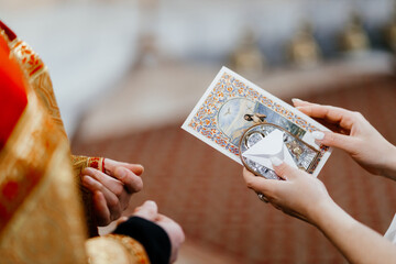  Mom's young hands are holding the icon. The sacrament of baptism. Close-up photo.