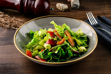 Fresh green salad in bowl on wooden table