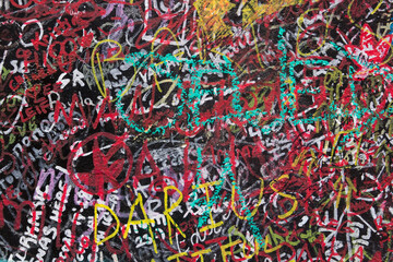 black wall is painted with small multi-colored graffiti