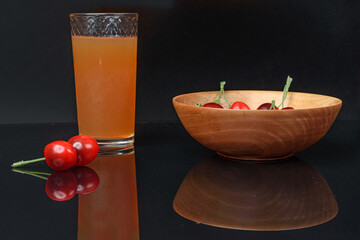 A glass of juice and decorative fruit on a black background close-up