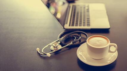 Coffee placed on the desk beside the computer, laptop and Earpiece