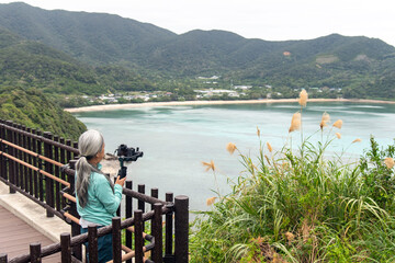 奄美大島のマネン崎展望広場で動画撮影をする女性フォトグラファー