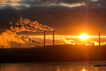 sunset and evening clouds against the backdrop of factory smoking chimneys