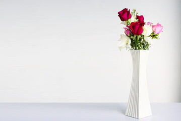Flowers in white vase on white table and white wall