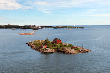 Aerial view on little islands with tiny red houses in Scandinavian style among the vast water ocean...