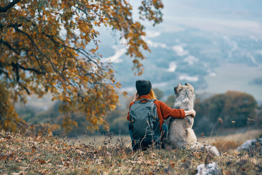 woman with dog sit on the ground in nature mountains