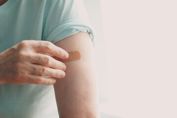 Vaccination elderly woman in doctor office with adhesive covid-19 vaccine plaster