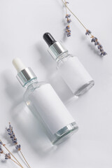 Cosmetics boottle with pipets with lavender flower on white background.