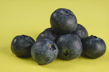 Heap of blueberries on yellow background