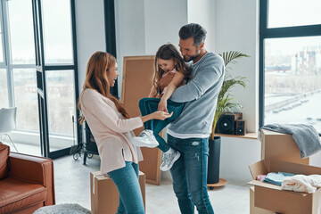 Fototapeta premium Playful young family bonding together while moving into a new apartment