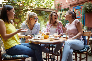 A group of female students are laughing while spending a good time in the bar's garden. Leisure,...