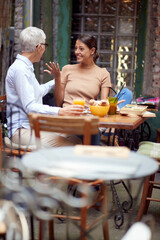 An older woman and her young female friend are so excited while talking in the bar. Leisure, bar, friendship, outdoor