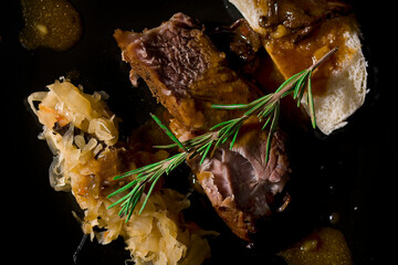 pork neck on a black plate, served with dumplings and cabbage with mushrooms